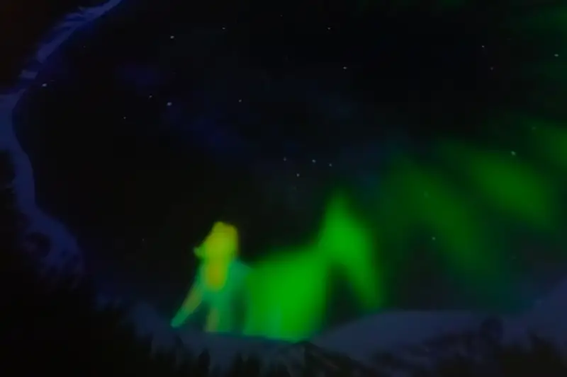 Green northern lights over snowy ground near Rovaniemi, Finland